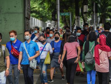 Orang-orang yang mengenakan masker menyeberang jalan di Manila, sehari sebelum pihak berwenang mencabut perintah tinggal di rumah pada Selasa (7/9/2021). Filipina akan mencabut lockdown di ibu kota Manila pada Rabu (8/9), saat kasus corona harian naik dua kali lipat. (Ted ALJIBE/AFP)