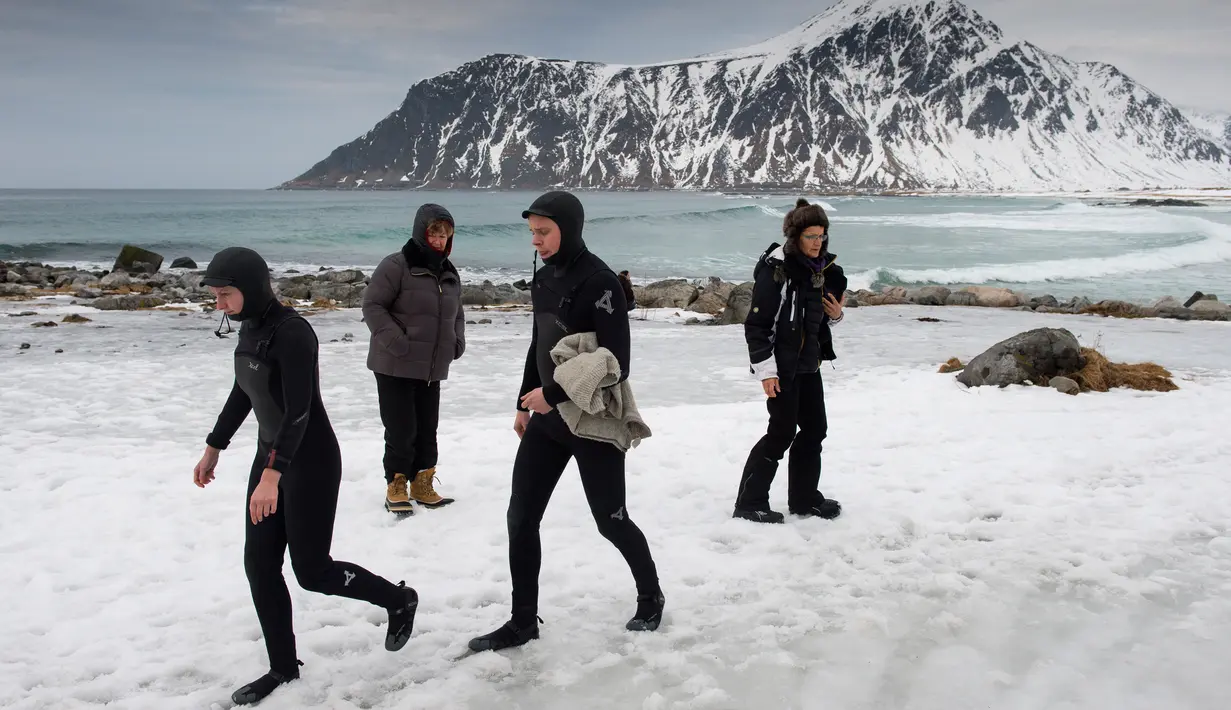 Sejumlah peselancar usai berselancar di pantai bersalju Flackstad di Kepulauan Lofoten, Lingkar Arktik, pada 13 Maret 2016. Suhu dingin memberikan sensasi tersendiri bagi peselancar terlepas dari cuaca yang sangat tidak stabil. (AFP/Olivier Morin)