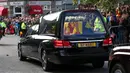 Warga berbaris saat mobil yang membawa peti berisi jenazah Ratu Elizabeth II melintas di Ballater, Skotlandia, Minggu (11/9/2022). Jenazah Ratu Elizabeth II diberangkatkan dari Kastil Balmoral ke Istana Holyroodhouse di Edinburgh sebelum nantinya akan dipindahkan ke London. (AP Photo/Scott Heppell)