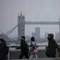 Pekerja berjalan di atas Jembatan London menuju distrik keuangan Kota London, dengan latar belakang Tower Bridge, pada jam sibuk pagi hari, Senin (24/1/2022). Inggris telah meminta orang-orang untuk kembali bekerja di kantor saat mereka melonggarkan pembatasan corona COVID-19. (AP Photo/Matt Dunham)