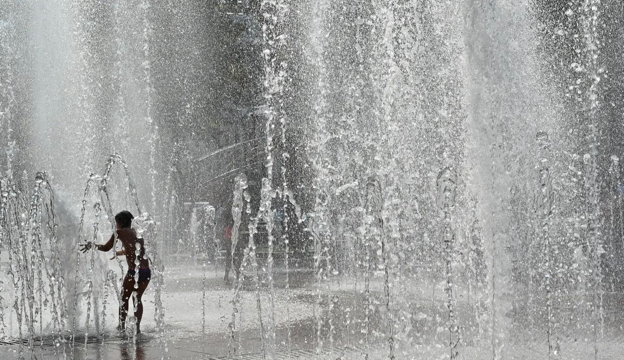 Seorang anak bermain di air mancur selama gelombang panas di Kiev, Ukraina (20/8/2019). Panasnya cuaca yang ekstrem membuat anak-anak menyejukkan diri mereka di bawah guyuran air mancur. (AFP Photo/Sergei Supinsky)