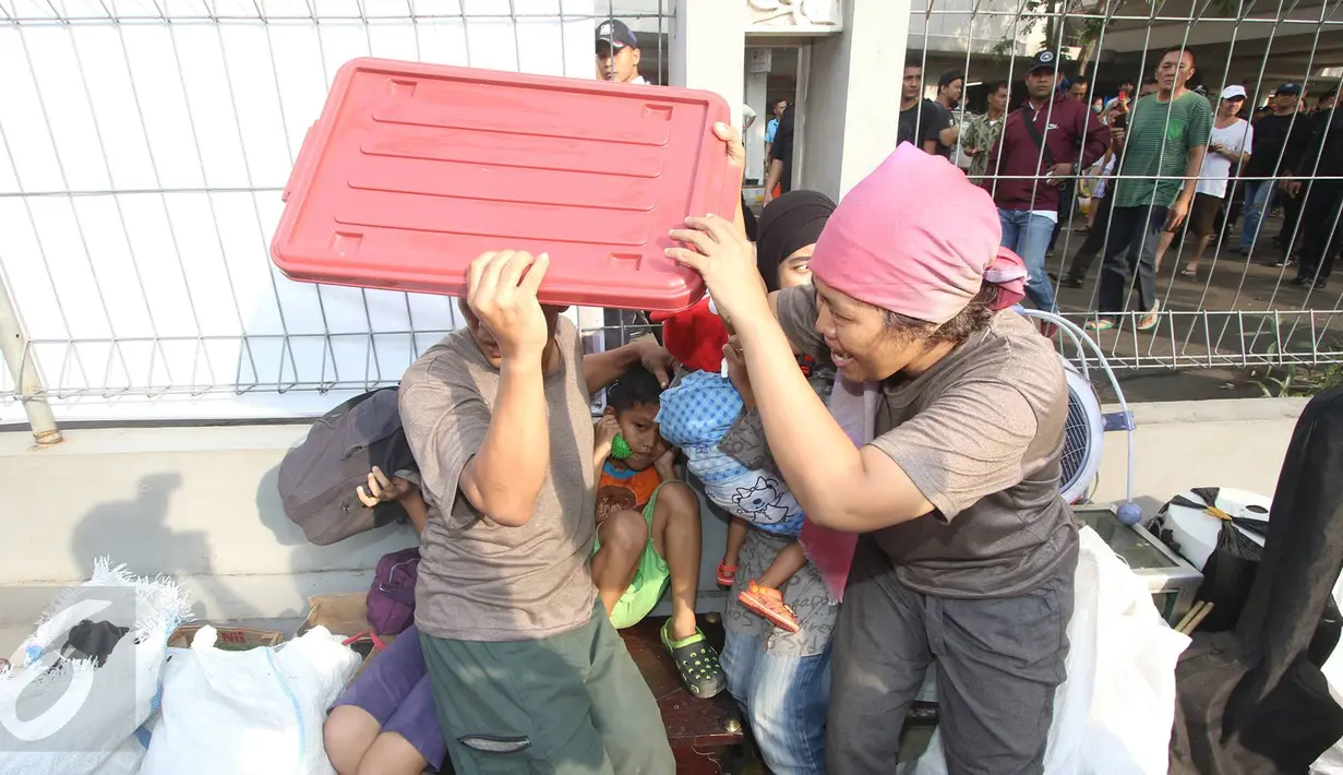 Warga melindungi diri saat bentrokan mewarnai eksekusi penggusuran oleh Satpol PP di kawasan Rawajati, Pancoran, Jakarta, Kamis (1/9). Warga yang menolak penggusuran dan aparat saling beradu mulut hingga berujung bentrokan (Liputan6.com/Immanuel Antonius)