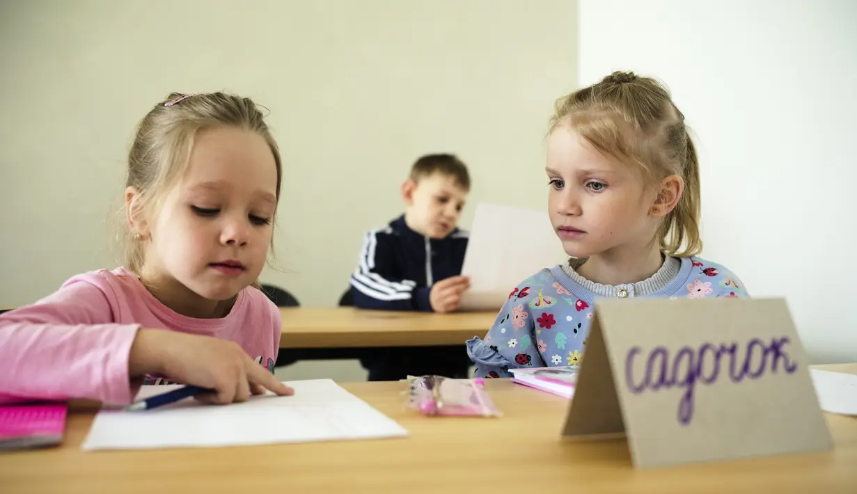 Dua anak menghadiri kelas untuk pengungsi dari Ukraina di Berlin, Jerman, Senin (21/3/2022). Kedua kelas privat pengungsi tersebut disatukan oleh dua relawan Berlin yang berhasil menggalang dana dan mendapatkan ruang kelas gratis. (AP Photo/Markus Schreiber)