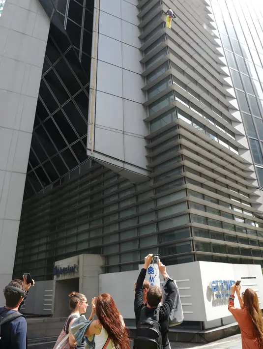 Warga menyaksikan aksi pendaki Prancis, Alain Robert memanjat Menara Internasional GT berlantai 47 di Makati City, Manila, Filipina (29/1). (AFP Photo/Ted Aljibe)