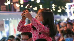 Seorang anak mengambil foto di sebuah pasar malam di Shanghai, China timur (6/6/2020). Sejumlah bar, museum, toko buku, pusat perbelanjaan, dan kompleks komersial besar ikut serta dalam festival itu dengan jam operasional yang diperpanjang. (Xinhua/Ding Ting)