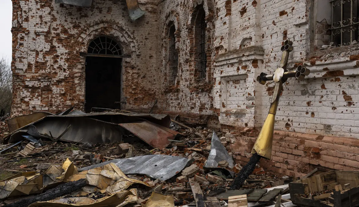 <p>Sebuah salib logam yang dulunya berada di atas kubah berdiri di luar gereja yang rusak di Lukashivka, di Ukraina utara, 22 April 2022. Penduduk mengatakan tentara Rusia menggunakan rumah ibadah untuk menyimpan amunisi, dan pasukan Ukraina menembaki gedung itu untuk membuat Rusia pergi. (AP Photo/Petros Giannakouris)</p>