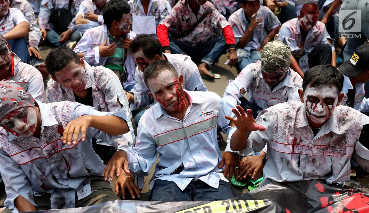 Massa buruh awak mobil tangki (AMT) berdandan seperti zombi melakukan aksi di depan gedung Pertamina, Jakarta, Senin (23/10). (Liputan6.com/Angga Yuniar)