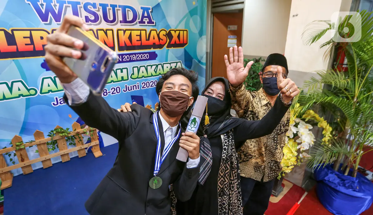 Siswa bersama kedua orang tua berswafoto usai Wisuda Pelepasan Kelas XII di Sekolah Aliyah Annajah, Petukangan, Jakarta, Kamis (18/6/2020). Pandemi Covid-19, Annajah menerapkan Wisuda Drive Thru untuk menghindari kerumunan sebagai upaya mencegah penyebaran virus Covid-19. (Liputan6.com/Fery Pradolo)