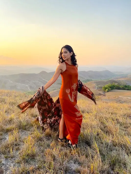 Aurelie Moeremans berpose dengan latar pemandangan alam yang luar biasa. Ia mengenakan sebuah dress tanpa lengan bercorak tradisional, dengan kain wastra yang senada. [Foto: Instagram/aurelie]