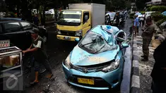 Satu unit taksi ringsek tertimpa pohon tumbang di Jalan Taman Kebon Sirih, Jakarta, Selasa (30/8). Pohon yang batangnya besar tersebut tumbang akibat hujan deras disertai angin kencang yang melanda Jakarta tadi siang. (Liputan6.com/Faizal Fanani) 