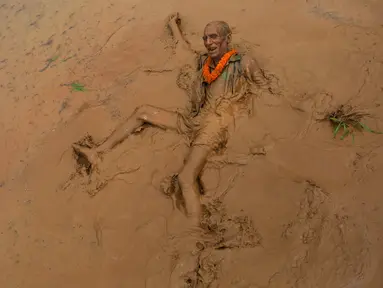 Seorang lelaki tua jatuh ke lumpur sawah saat merayakan Asar Pandra atau hari menanam padi di Distrik Dhading, Nepal, Minggu (30/6/2019). Umat Hindu Nepal menganggap Asar Pandra sebagai hari baik untuk menanam padi. (AP Photo/Niranjan Shrestha)
