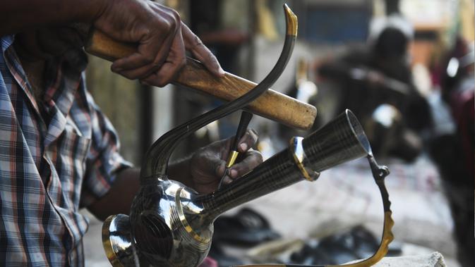 Perajin membuat kerajinan teko dari kuningan di sebuah bengkel di Karachi (19/11/2019). Karachi merupakan salah satu pusat kerajinan kuningan terbaik di Pakistan. (AFP Photo/Asif Hassan)