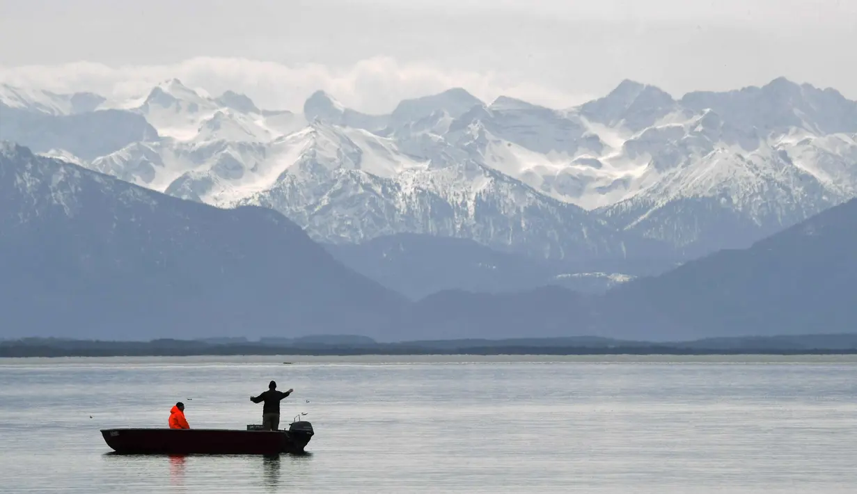 Nelayan menyiapkan jaring untuk menangkap ikan di depan pegunungan Alp di danau Starnberger See dekat desa Starnberg, Jerman selatan, selama cuaca musim semi yang bagus dengan suhu 15 derajat pada 3 April 2018. (AFP Photo/Christof Stache)