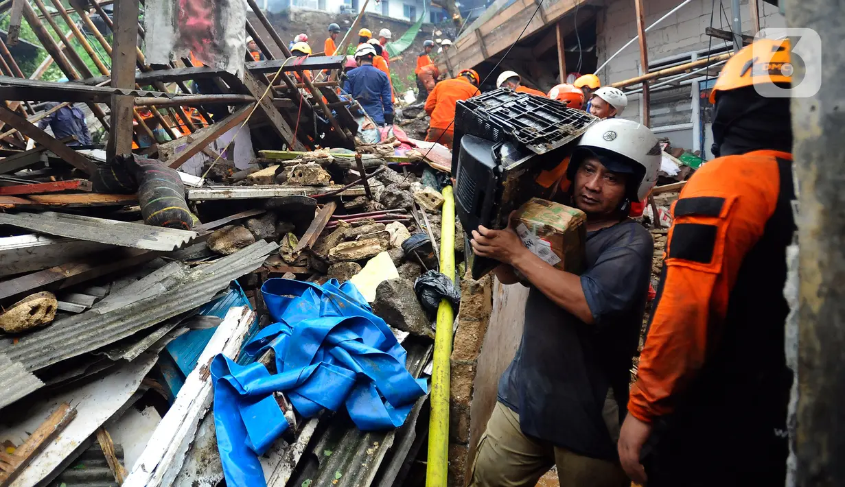 Warga membawa TV di lokasi warga yang tertimbun longsor di  Kampung Kebon Jahe, Kelurahan Kebon Kelapa, Kecamatan Bogor Tengah, Jawa Barat, Kamis (13/10/2022). Hingga jelang malam hari, Tim SAR mengalami kesulitan menemukan tiga warga yang hilang akibat lokasi longsor berada pada gang kecil sehingga pencarian dilakukan secara manual  ditambah kondisi cuaca hujan. (merdeka.com/Arie Basuki)