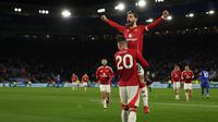 Gelandang Manchester United, Bruno Fernandes melompat ke pelukan Diogo Dalot saat merayakan gol ketiga mereka pada pertandingan pekan ke-29 Premier League 2024/2025 melawan Leicester City di King Power Stadium, Inggris pada 16 Maret 2025 waktu setempat atau Senin (17/3/2025) dini hari WIB. (Adrian Dennis/AFP)