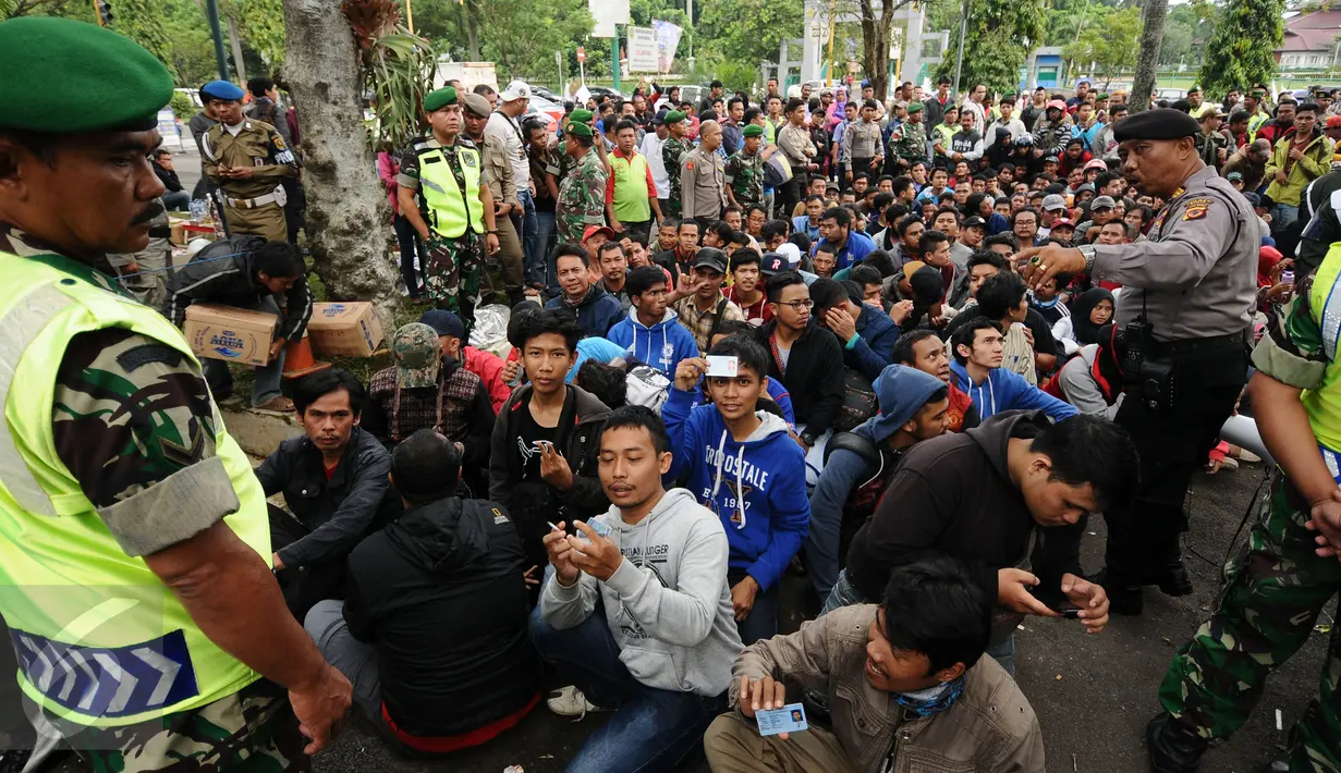 Petugas gabungan mengatur suporter yang antri masuk ke halaman Kodim 0621 Surya Kancana Kab Bogor, Selasa (13/12). 5000 lembar tiket final Piala AFF 2016 antara Indonesia vs Thailand dijual di Kodim 0621 Surya Kancana. (Liputan6.com/Helmi Fithriansyah)