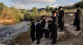 Yahudi ultraortodoks berpartisipasi dalam upacara Tashlich di tepi sungai dekat Beit Shemesh, Israel, Rabu (20/9/2023). Tashlich, yang berarti 'membuang' dalam bahasa Ibrani, adalah praktik di mana orang Yahudi pergi ke perairan besar yang mengalir dan secara simbolis 'membuang' dosa mereka dengan melemparkan sepotong roti atau makanan serupa ke dalam air. (AP Photo/Ohad Zwigenberg)