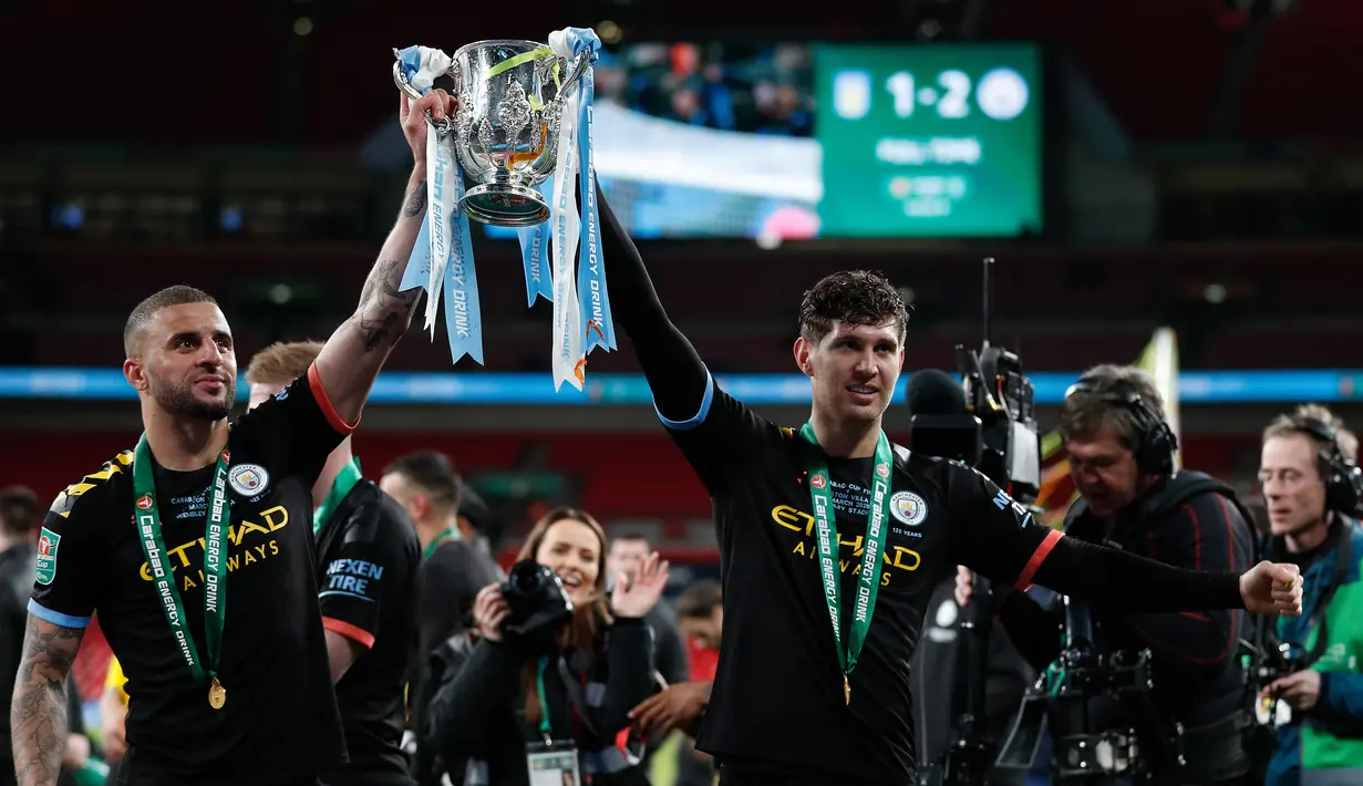 Bek Manchester City Kyle Walker (kiri) dan rekan setimnya,  John Stones merayakan kemenangan laga final Piala Liga Inggris setelah mengalahkan Aston Villa di Stadion Wembley, Minggu (1/3/2020). Manchester City menjuarai Piala Liga Inggris usai menang 2-1 atas Aston Villa. (Adrian DENNIS/AFP)