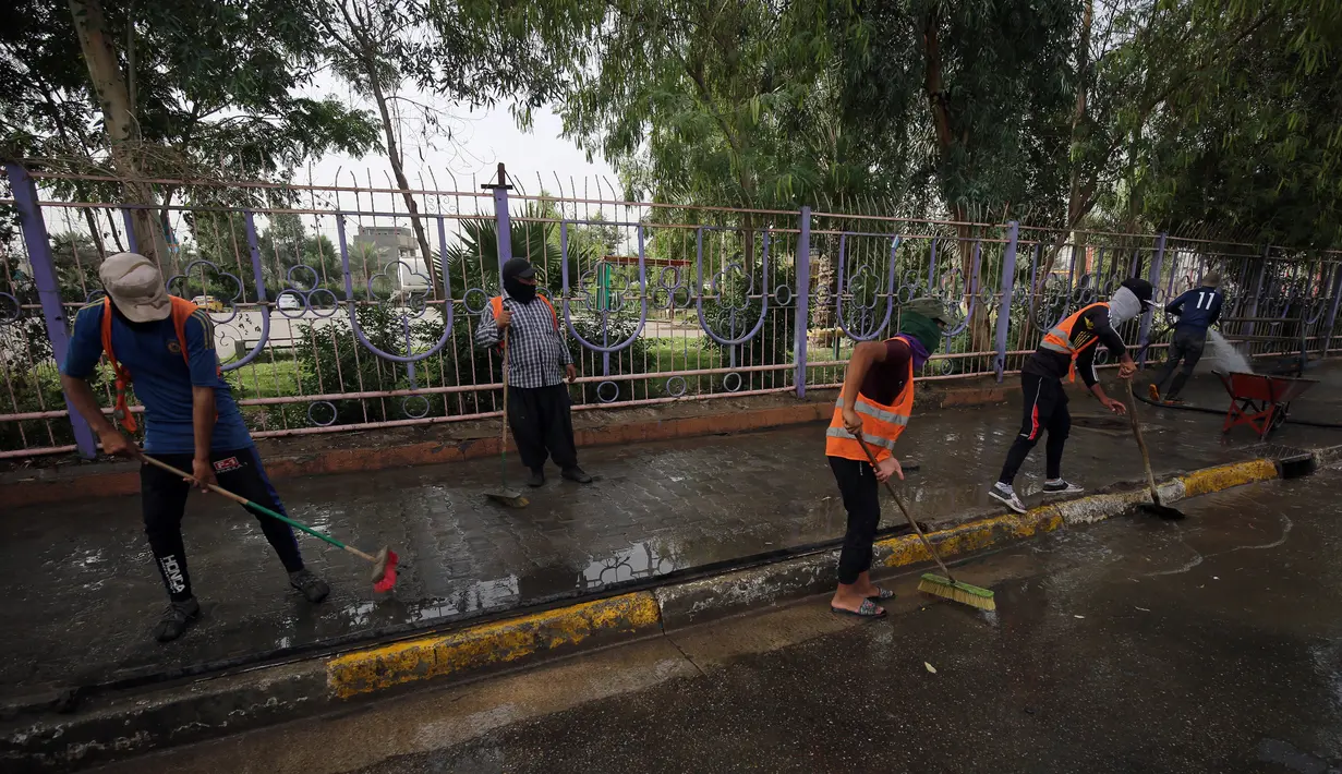 Pekerja kota Irak membersihkan jalanan setelah serangan bom bunuh diri semalam di Syiah Baghdad di al-Shoala (24/5). Empat orang tewas dan beberapa lainnya terluka ketika seorang pembom bunuh diri menyerang kafe di Baghdad. (AFP Photo/Ahmad Al-Rubaye)