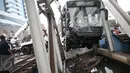 Alat berat mengangkat badan bus transjakarta yang terperosok ke sungai usai ditabrak kereta Senja Utama Solo di perlintasan Jalan Mangga Dua, Jakarta, Kamis (19/5). Sopir Transjakarta, Adil Setiawan mengalami luka berat. (Liputan6.com/Faizal Fanani)