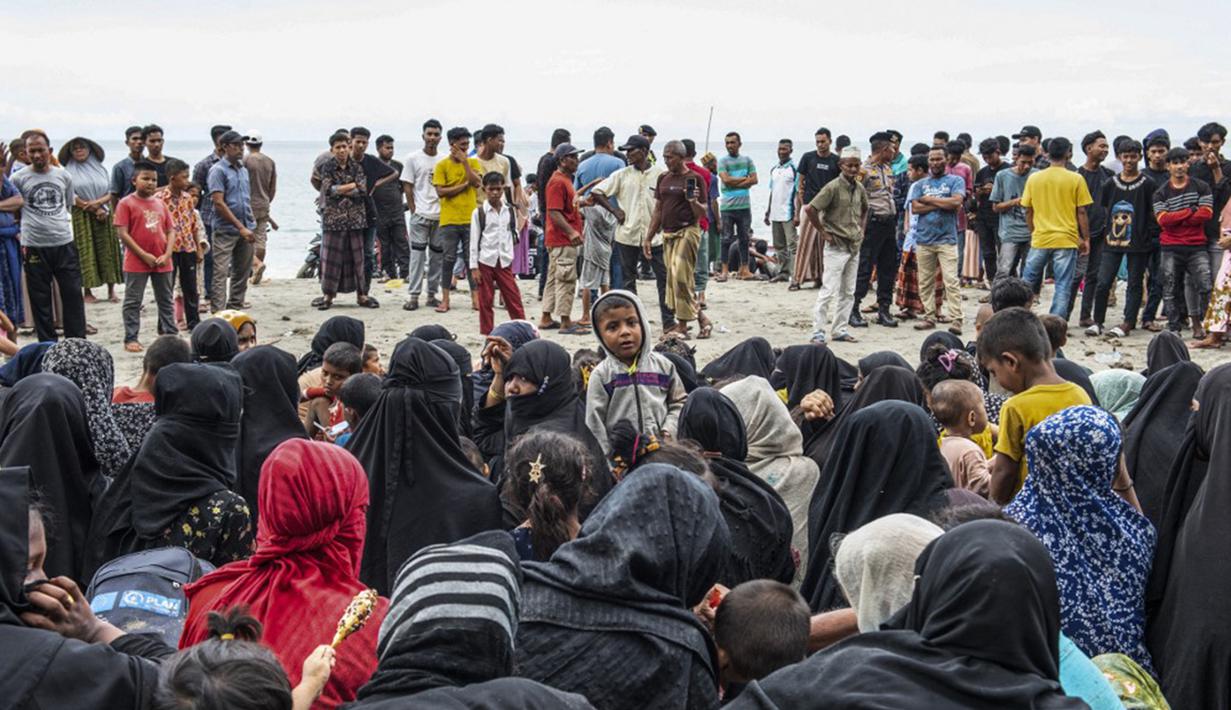 Pengungsi Rohingya duduk bersama di tanah setelah mereka tiba dengan perahu di Pantai Kalee, Laweung, Kabupaten Pidie, Provinsi Aceh, Indonesia, Selasa (14/11/2023). Hampir 200 pengungsi Rohingya, termasuk banyak perempuan dan anak-anak, terdampar di provinsi paling barat Indonesia pada 14 November, menurut laporan setempat. (Jon S./AFP)
