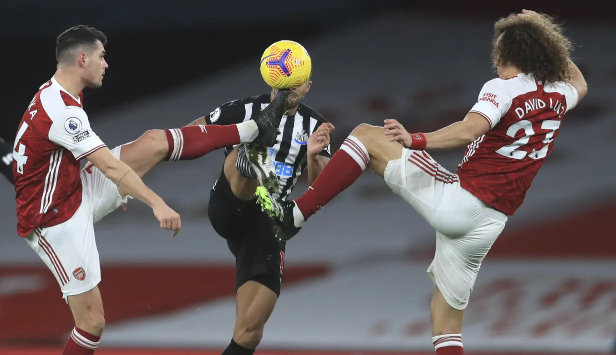 Penyerang Newcastle United, Callum Wilson berebut bola dengan dua pemain Arsenal Granit Xhaka dan David Luiz pada pertandingan Liga Inggris di Stadion Emirates di London, Selasa (19/1/2021). Arsenal menang telak atas Newcastle 3-0. (Adam Davy/Pool via AP)