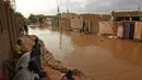 Penduduk Sudan duduk di luar rumah mereka yang banjir di daerah alqamayir di kota kembar ibu kota Omdurman (26/8/2020). (AFP Photo/Ashraf Shazly)