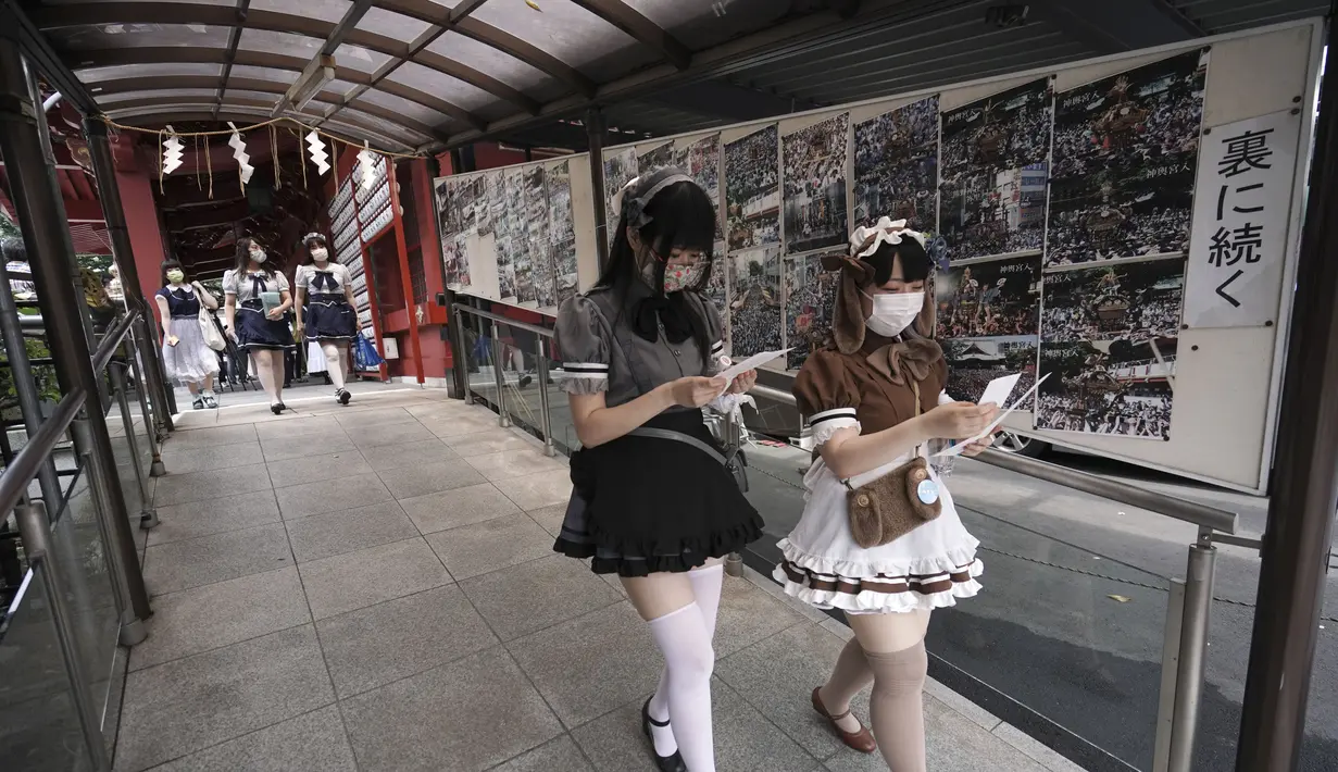 Karyawan mengenakan kostum pelayan dari beberapa kafe bertema pembantu di Akihabara berjalan setelah pertemuan doa untuk perlindungan dari COVID-19 dan untuk bisnis yang berkembang di kuil Kanda Myojin, Tokyo (25/7/2020). (AP Photo/Eugene Hoshiko)