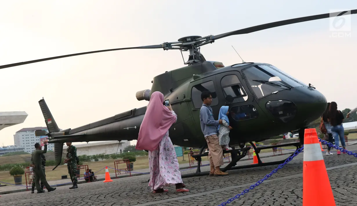 Warga berfoto berlatar helikopter TNI pada pameran Alat Utama Sistem Persenjataan TNI di Kawasan Monas, Jakarta, Kamis (27/9). Pameran ini bagian perayaan HUT TNI ke-73. (Liputan6.com/Helmi Fithriansyah)