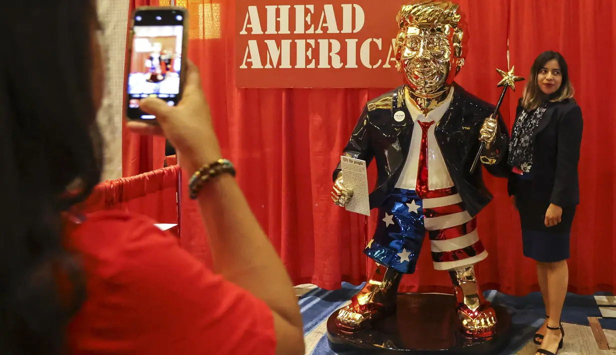 Seorang perempuan berfoto dengan patung emas Donald Trump pada Konferensi Politik Konservatif (CPAC) di Orlando, Florida, Jumat (26/2/2021). Kemunculan patung emas yang lebih besar dari ukuran pria dewasa di acara tersebut menjadi viral. (Sam Thomas/Orlando Sentinel via AP)