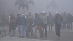 Orang-orang berjalan di sepanjang jalan Heritage di tengah kondisi berkabut pada Hari Tahun Baru, di Amritsar (1/1/2021). Sebagian besar India utara mencatat suhu yang menusuk tulang dan diselimuti kabut tebal sementara di Kashmir diselimuti salju pada Hari Tahun Baru. (AFP/Narinder Nanu)