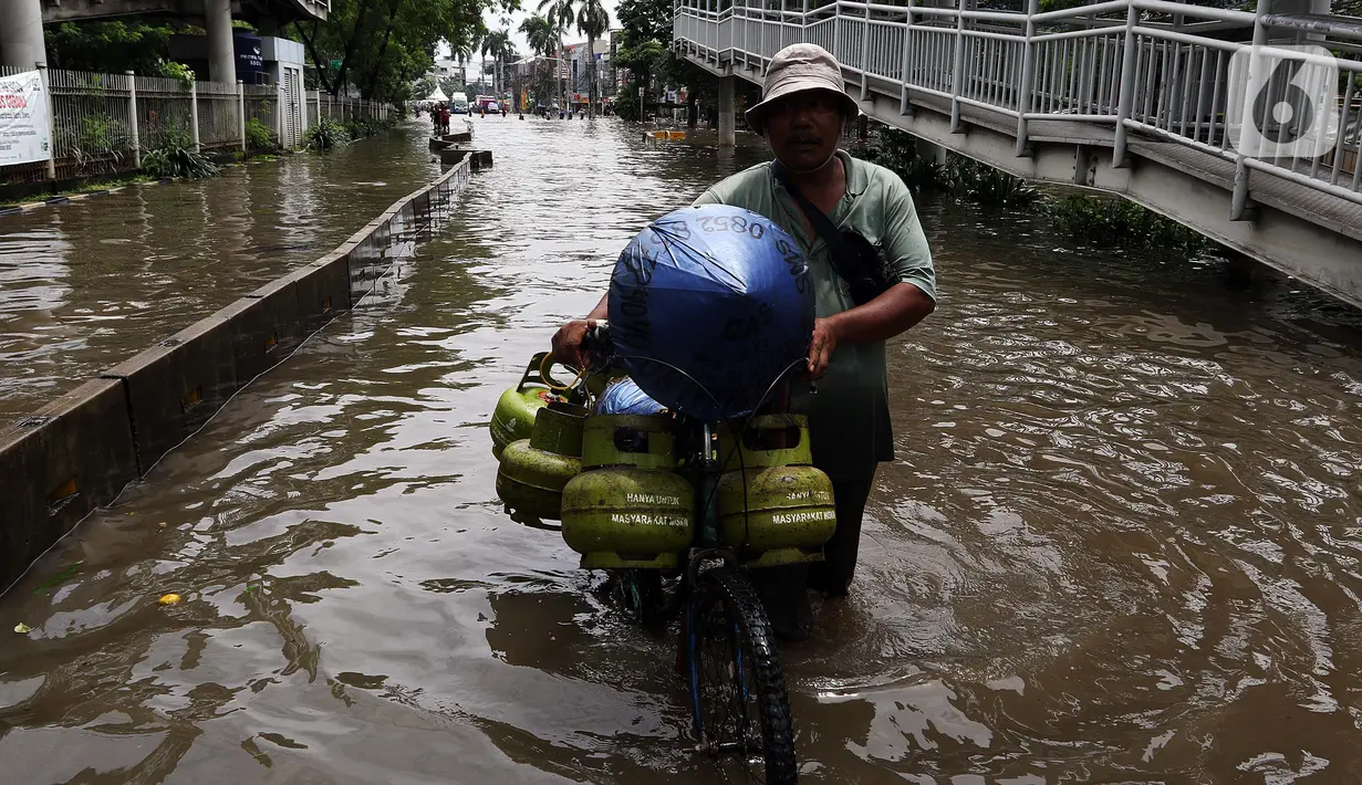 Seorang pria mendorong sepedanya melintasi banjir di kawasan Green Garden, Jakarta Barat, Selasa (25/2/2020). Hujan yang mengguyur kawasan Jakarta membuat kawasan tersebut tergenang banjir setinggi 60-80 cm. (Liputan6.com/Johan Tallo)