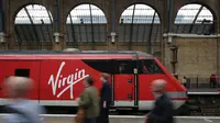 Penumpang kereta api melewati kereta yang dioperasikan oleh layanan jalur utama Virgin Trains East Coast berada di stasiun kereta London Kings Cross di London pada 16 Mei 2018. (Dok: AFP)