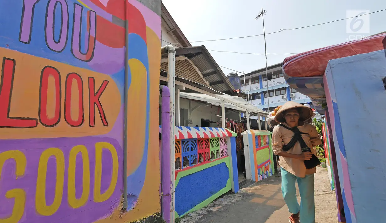 Seorang pedagang melintasi gang sempit yang sisi tembok dindingnya dihiasi lukisan mural warna-warni di Kampung Pejaten, Jakarta, Senin (30/4). Mural motif warna-warni itu digagas warga untuk memperindah kampung mereka. (Liputan6.com/Herman Zakharia)