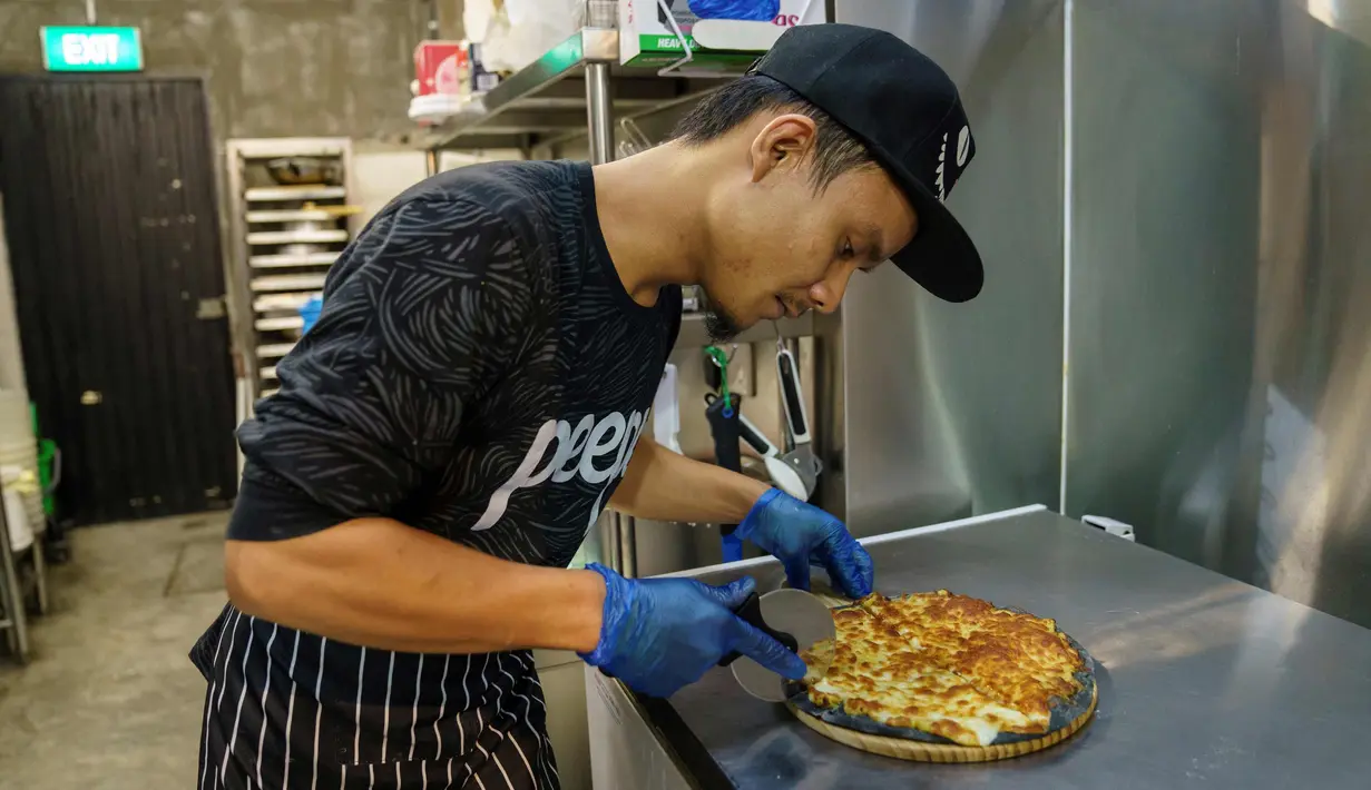 Seorang anggota staf menyiapkan pizza rasa durian di kafe Mao Shan Wang di distrik Chinatown, Singapura (24/1). (AFP Photo/Nicholas Yeo)