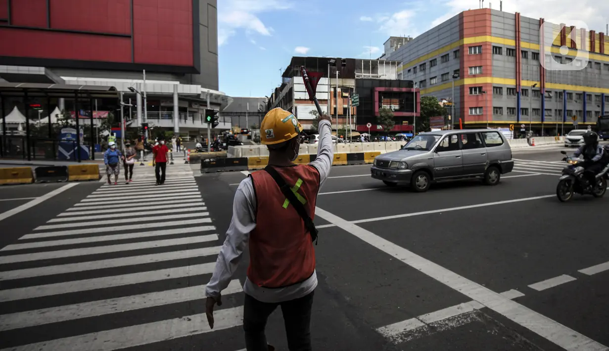 Petugas mengatur lalu lintas untuk warga menyeberang jalan menggunakan pelican crossing di kawasan Glodok, Jakarta, Sabtu (22/1/2022). PT Transportasi mulai mengoperasikan Halte Glodok baru dengan rute Blok M - Kota (Koridor 1). (Liputan6.com/Johan Tallo)