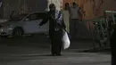 Seorang wanita mengenakan masker saat berbelanja di toko bahan makanan selama penguncian yang diberlakukan selama pandemi virus corona, di kamp pengungsi Shati, di Kota Gaza, Selasa, (1/9/2020). (AP Photo/Adel Hana)