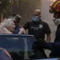 Petugas pemadam kebakaran dan polisi mengevakuasi seorang perempuan lansia dari rumahnya di kawasan yang dilanda kebakaran hutan di kota Penteli, timur laut Athena, Yunani. (Foto: AP)