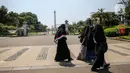 Sejumlah warga berjalan di depan kawasan Monumen Nasional (Monas), Jakarta, Minggu (26/7/2020). Sejumlah warga mulai mengunjungi kawasan Monas meski masih ditutup sementara di masa PSBB transisi. (Liputan6.com/Faizal Fanani)