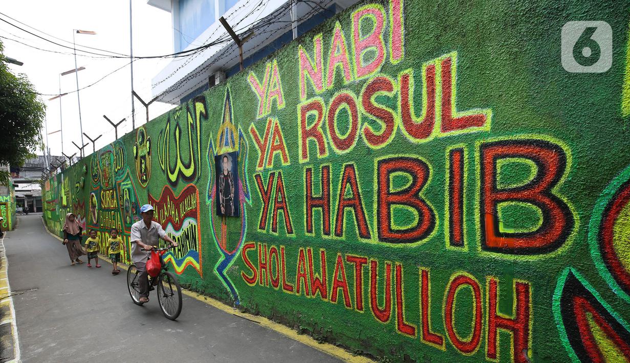 Warga berjalan di depan mural bernuansa Islami di Gang Pelangi, kawasan Kalibata, Jakarta, Jumat (23/4/2021). Mural bernuansa Islami tersebut dibuat warga untuk menghiasi dan meramaikan pintu masuk gang dalam rangka menyambut bulan Ramadhan. (Liputan6.com/Herman Zakharia)
