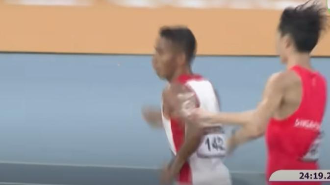 <p>Pelari Singapura Soh Rui Yong memberikan air ke pelari Indonesia Rikki Marthin Luther Simbolon di tengah perlombaan lari 10.000 meter pria di SEA Games 2023. Soh yang berada di belakang Rikki memberikan sedikit airnya ke Rikki setelah pelari Indonesia itu gagal mengambil air karena berlari sangat kencang. (Foto: Capture video YouTube @mediacorp). </p>