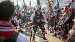 Seorang penari atau "Kukeri" melakukan gerakan tarian saat mengikuti Festival Internasional Masquerade Games di Pernik, Bulgaria (28/1). Para peserta mengenakan topeng dan aksesoris yang dipenuhi manik-manik dan pita. (AFP/Nikolay Doychinov)