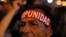 Seorang demonstran mengenakan ikat kepala yang bertuliskan "Impunity" saat berujuk rasa menuntut presiden Honduras,  Juan Hernandez untuk mundur atas dugaan korupsi senilai  US$ 200 juta di Tegucigalpa, Jumat (24/7/2015).  (REUTERS/Jorge Cabrera)