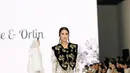 Ia tampil feminin mengenakan long dress lengan panjang warna putih dengan motif floral yang indah.