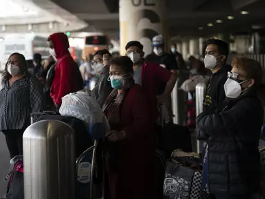 Pelancong menunggu bus antar-jemput tiba di Bandara Internasional Los Angeles di Los Angeles, Senin (20/12/2021). Departemen Kesehatan Masyarakat Los Angeles County melaporkan lebih dari 3.500 kasus baru COVID-19 pada hari Minggu. (AP Photo/Jae C.Hong)