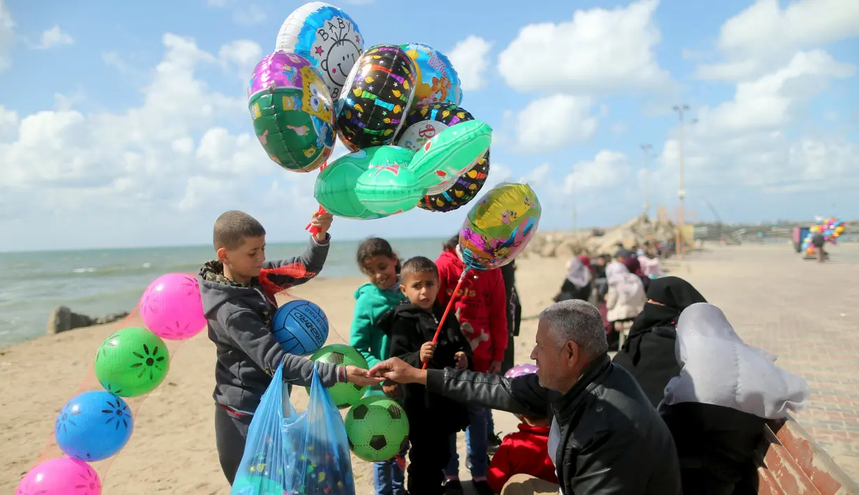 Seorang anak Palestina, Mahmoud al-Hindawi (15) menjual balon dan bola di Pelabuhan Kota Gaza (17/3). Hindawi yang masih bersekolah menghasilkan sekitar 25 Shekels ($6.4) per hari kerja karena ayahnya sudah lagi tidak bekerja. (REUTERS/Mohammed Salem)