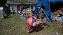 Seorang pengungsi letusan gunung Semeru mengumpulkan jatah makanan mereka di tempat penampungan sementara di desa Sumber Wuluh di Lumajang, Jawa Timur, Senin (6/12/2021). Tim SAR Gabungan masih terus melakukan proses pencarian warga yang hilang. (Juni Kriswanto/AFP)