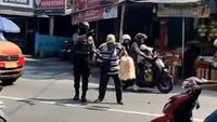 Ipda Suwinta saat membantu pria lansia penjual kerupuk pikul menyeberang jalan. (Liputan6.com/ Dok Ist)