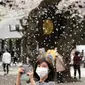 Seorang pengunjung berfoto di bawah pancuran bunga sakura yang mekar penuh di kuil shinto di Tokyo, Kamis (31/3/2022). (AP Photo/Shuji Kajiyama)