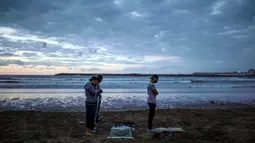 Sejumlah pria salat Maghrib berjamaah usai buka puasa bersama di pantai Rabat, Maroko (9/6). Selama Ramadan, banyak warga Maroko berkunjung ke pantai menikmati angin Atlantik dan menikmati pemandangan laut. (AP Photo/Mosa'ab Elshamy)
